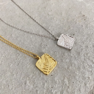 Detailed relief of fern leaf patterns on gold and silver square texture pendants