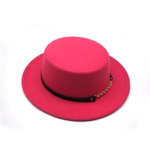 Detail of fuchsia wool felt boater hat with black leather strap and gold chain accent