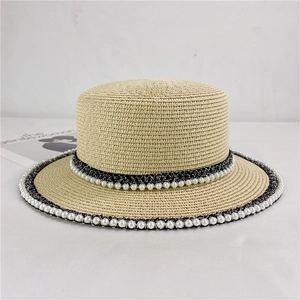 Close-up of woven straw boater hat with double-row faux pearl trim and black ribbon