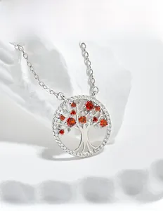 Detailed view of Tree of Life pendant with red gems and white cubic zirconia on white stone