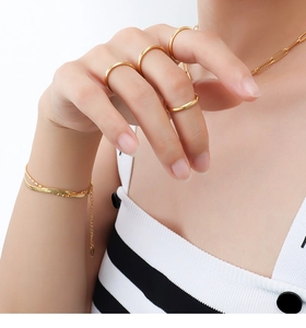 Polished 18K gold-plated titanium steel rings and bracelet worn by a model