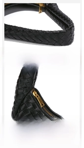 Close-up of woven black leather texture and gold triangle zipper on hobo bag