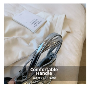 Detail of silver metallic handbag handles with precise stitching and pleated texture