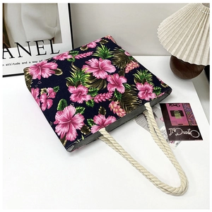Close-up of tropical floral tote bag with pink hibiscus print and beige rope handles