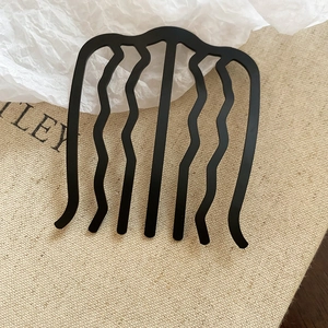 Vue détaillée d'un peigne à cheveux noir ondulé à sept dents avec finition mate