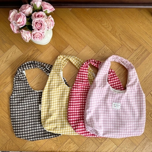 Close-up of four colorful plaid tote bags in brown yellow red and pink on wood floor