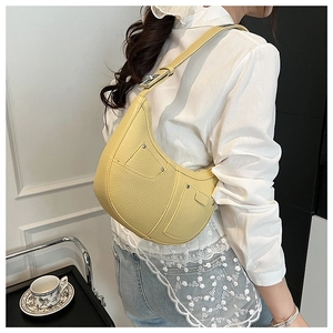 Close-up of yellow leather hobo bag with twin front pockets and metallic rivet details