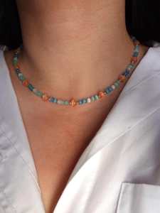 Detail shot of multicolor cat eye stone beads on necklace worn with a white shirt