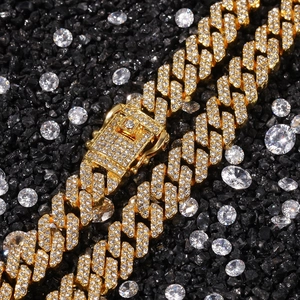 Macro detail of iced-out gold Cuban link necklace with white zircons on black stone