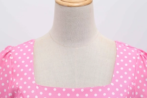 Detail of square neckline and white polka dots on pink vintage dress on a mannequin