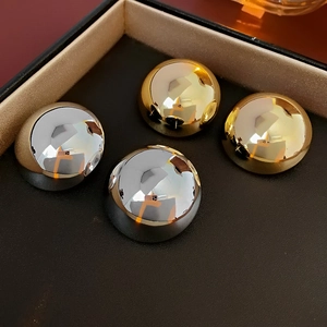 Detailed close-up of minimalist hemisphere stud earrings in gold and silver finishes