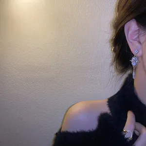 Close-up of teardrop zircon earrings and crystal ring on a model with soft lighting