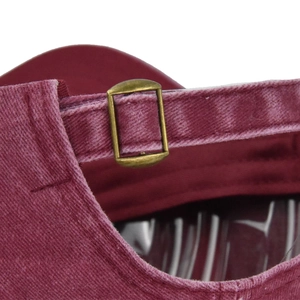 Detailed close-up of adjustable bronze metal buckle on washed cotton baseball cap