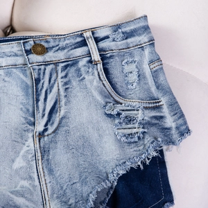 Primo piano di pantaloncini di jeans azzurri con strappi e dettaglio bottone metallico