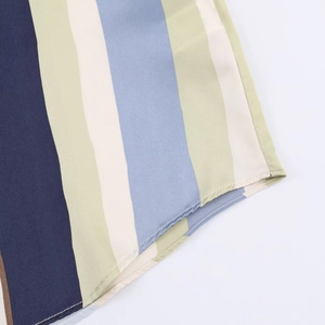 Detail of the hem featuring vertical stripes in navy, light green, and blue satin fabric