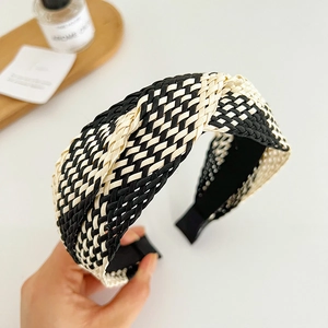 Détail du bandeau tressé à damier noir et beige avec un design élégant à nœud torsadé