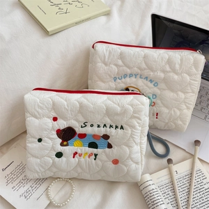 Close-up of cute puppy embroidery and heart quilted texture on white makeup bags