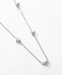 Macro shot of silver chain featuring four iridescent heart-shaped opal-like zircon stones