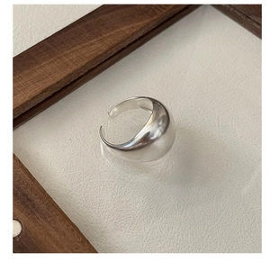 Close-up of a minimalist adjustable silver ring on a white textured background