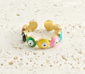Detail of 18k gold evil eye ring with colorful enamel dots on a white stone background