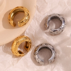 Detailed top view of gold and silver heart-embossed ear cuffs on textured paper