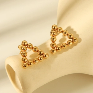 Macro shot of gold beaded triangle earrings with mirror finish and smooth metal luster