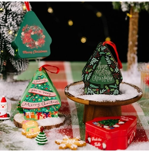 Detail view of festive house and tree shaped tin gift boxes with red ribbons and snow