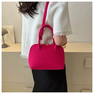 Rose red shell bag with crocodile texture worn as a stylish crossbody bag by a model