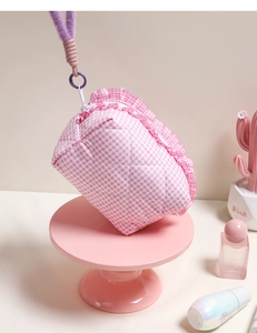 Detailed view of pink quilted cosmetic bag with ruffle trim and purple plush handle