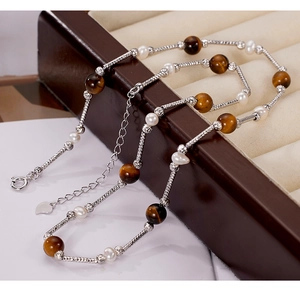 Detailed shot of 925 sterling silver tiger eye necklace with white pearls and heart charm