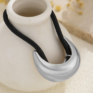 Close-up of a minimalist silver curved metal charm on a black high-elastic hair tie cord