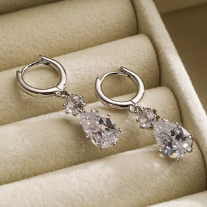 Elegant silver drop earrings with zircons in a beige jewelry box with a diagonal view