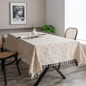 Macro detail of beige cotton linen tablecloth with floral patterns and fringe tassels