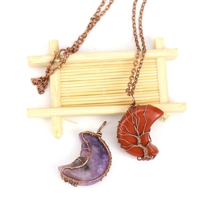 Close-up of handmade wire-wrapped moon pendants with natural crystals in purple and red-brown