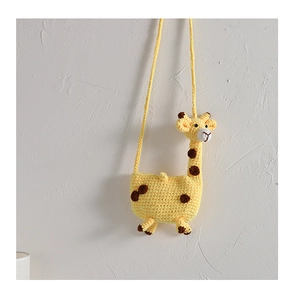Detail of yellow handmade crochet giraffe bag with brown spots on a white wall