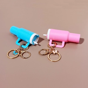 Miniature blue and pink bottle keychains with butterfly charms and lipstick holders