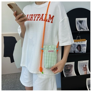 Detail der grün-weiß karierten Mini-Handytasche mit kräftigem orangefarbenem Seilgurt