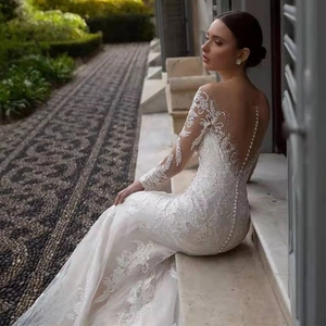 Elegant white lace mermaid wedding dress with deep V back and long sleeves in garden setting