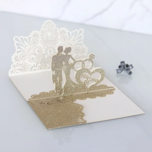 Macro detail of laser-cut 3D wedding card with gold glitter bride and groom silhouette