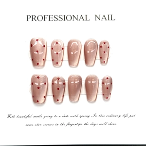 Detail of nude pink press-on nails with cat-eye effect and red polka dots on a display card