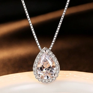 Macro detail of a 2-carat teardrop moissanite pendant with sparkling diamond halo