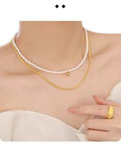 Detail of layered freshwater pearl necklace with gold chain and textured silver ring