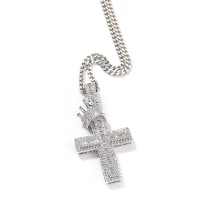 Detailed close-up of a silver crown cross pendant with cubic zirconia on a Cuban chain