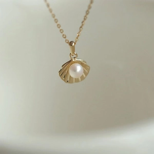 Macro shot of 14k gold plated S925 silver necklace with shell pendant and pearl inlay