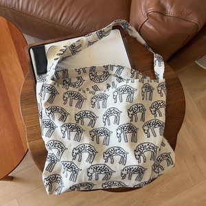 Close-up of cream canvas tote bag with black abstract animal print on a wooden tray