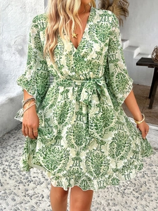 Detail of green and white printed chiffon dress with V-neck and belted waist for summer