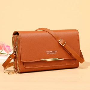 Detail view of brown leather crossbody phone bag with double zippers and golden hardware