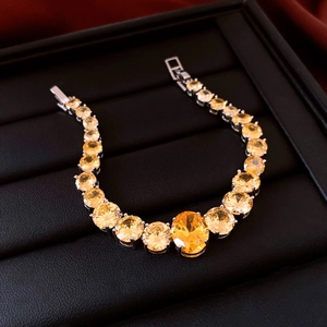 Detail of zircon heart bracelet featuring a yellow oval gemstone and silver claw setting