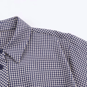 Détail d'une chemise à carreaux vichy bleu et blanc avec col à revers et boutons bleu marine