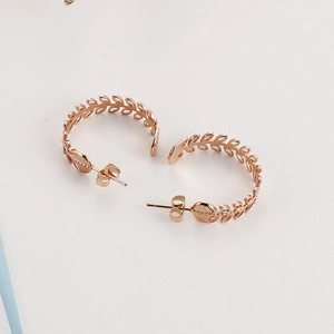 Detailansicht roségoldener C-förmiger Ohrringe mit filigranem, hohl gearbeitetem Blattdesign